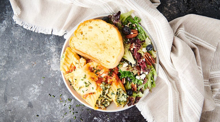 plate with manicotti, salad, and garlic bread above