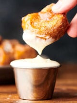 piece of monkey bread being dipped in frosting