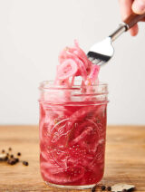 pickled red onions being lifted out of jar with fork