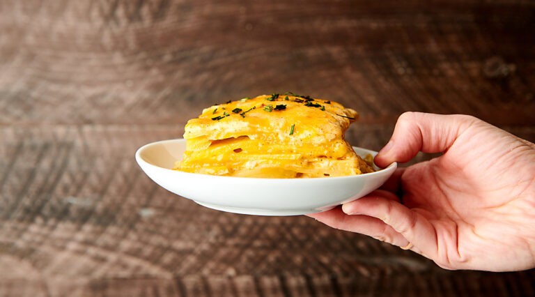 scalloped potatoes on plate held