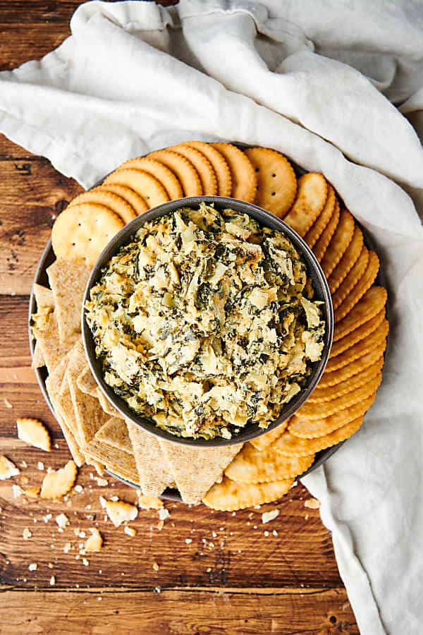 plate of crackers with bowl of spinach artichoke dip