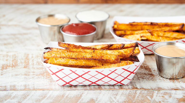 two dishes of air fryer french fries with condiments
