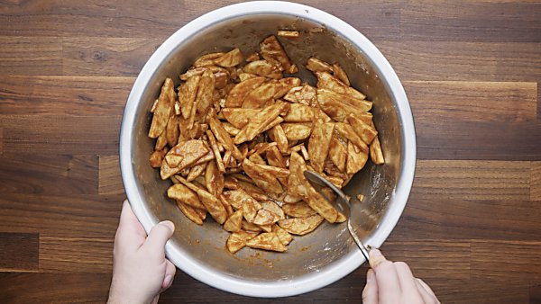 apple slices tossed with filling ingredients in large bowl