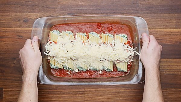 stuffed manicotti in baking dish with sauce and cheese