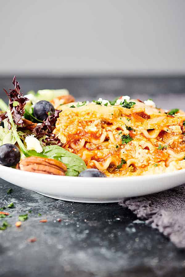 slice of vegetarian lasagna on plate with salad