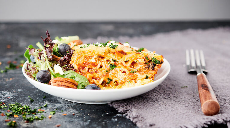 slice of lasagna on plate with salad