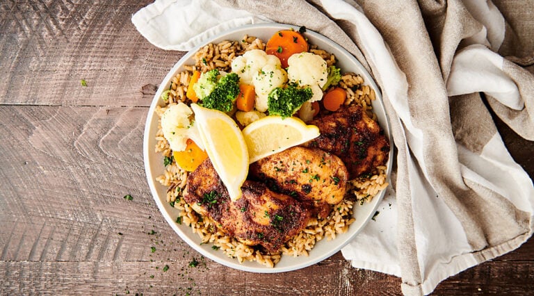 air fryer chicken thighs on plate with veggies and rice above