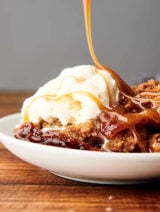 plate of apple cobbler being drizzled with caramel