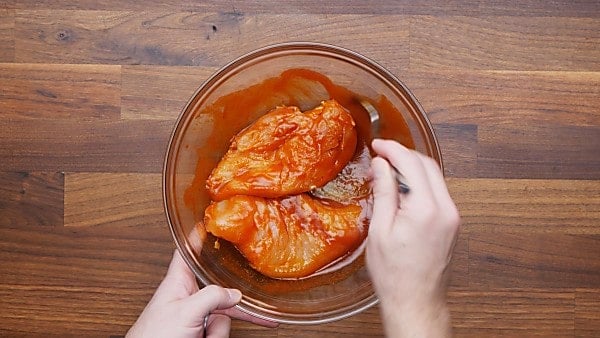chicken being tossed with buffalo sauce