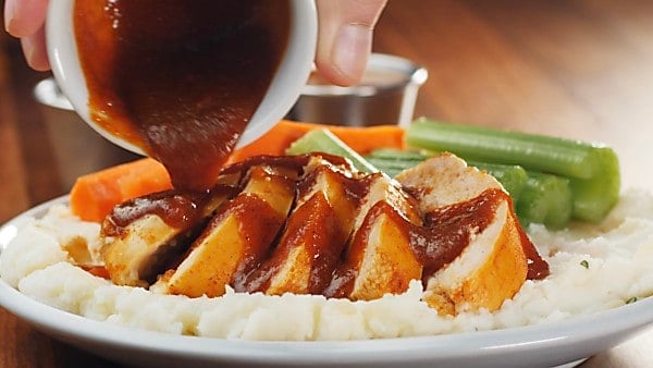 sliced chicken being drizzled with buffalo sauce