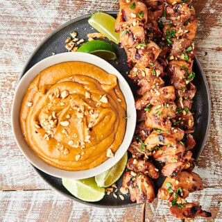 chicken satay skewers on plate with bowl of thai peanut sauce above