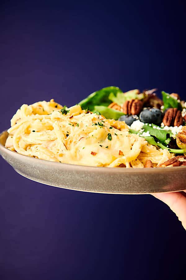 plate of chicken tetrazzini with salad held