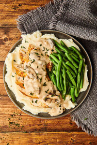marsala sauce over chicken and mashed potatoes on plate with green beans