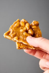 two pieces of peanut brittle held