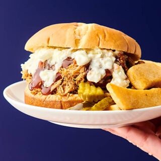 pulled pork sandwich on plate held blue background