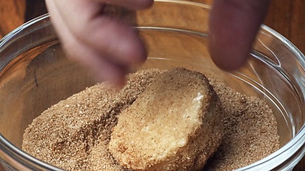 cookie dough ball being rolled in cinnamon/sugar