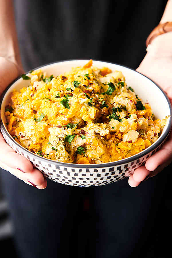 bowl of broccoli cheese casserole held two hands