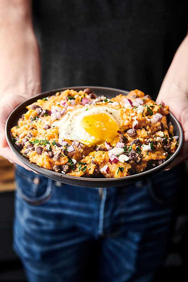 chilaquiles on plate with fried egg held