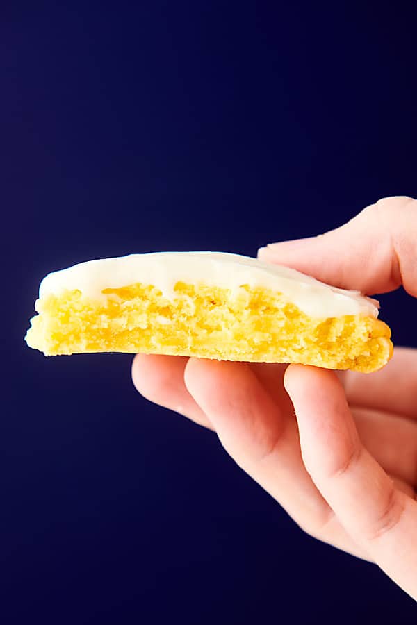 lemon cookie with bite out held blue background