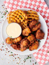 popcorn chicken with waffle fries and ranch on plate above