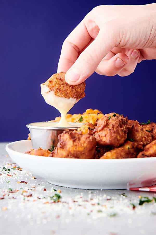 popcorn chicken on plate, one being dipped in ranch