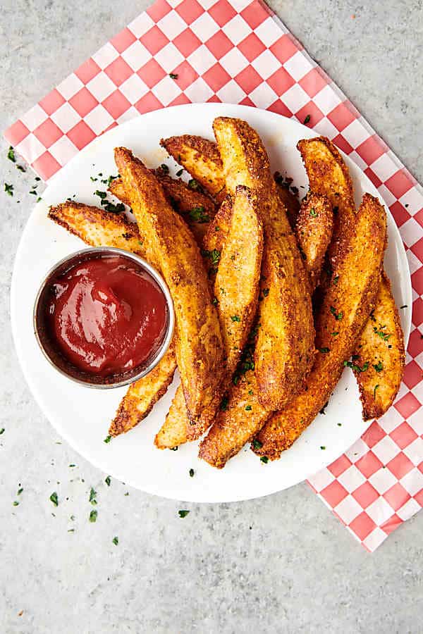 potato wedges on plate with ketchup above