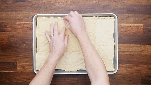crescent roll dough being prepped on baking sheet