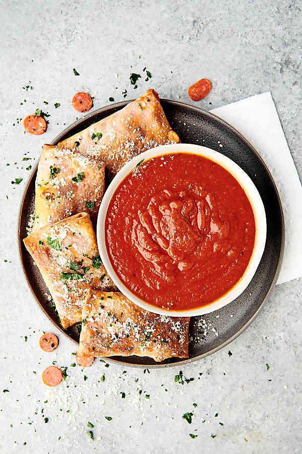 plate of air fryer pizza rolls with pizza sauce above