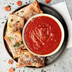 air fryer pizza rolls on plate with bowl of sauce above