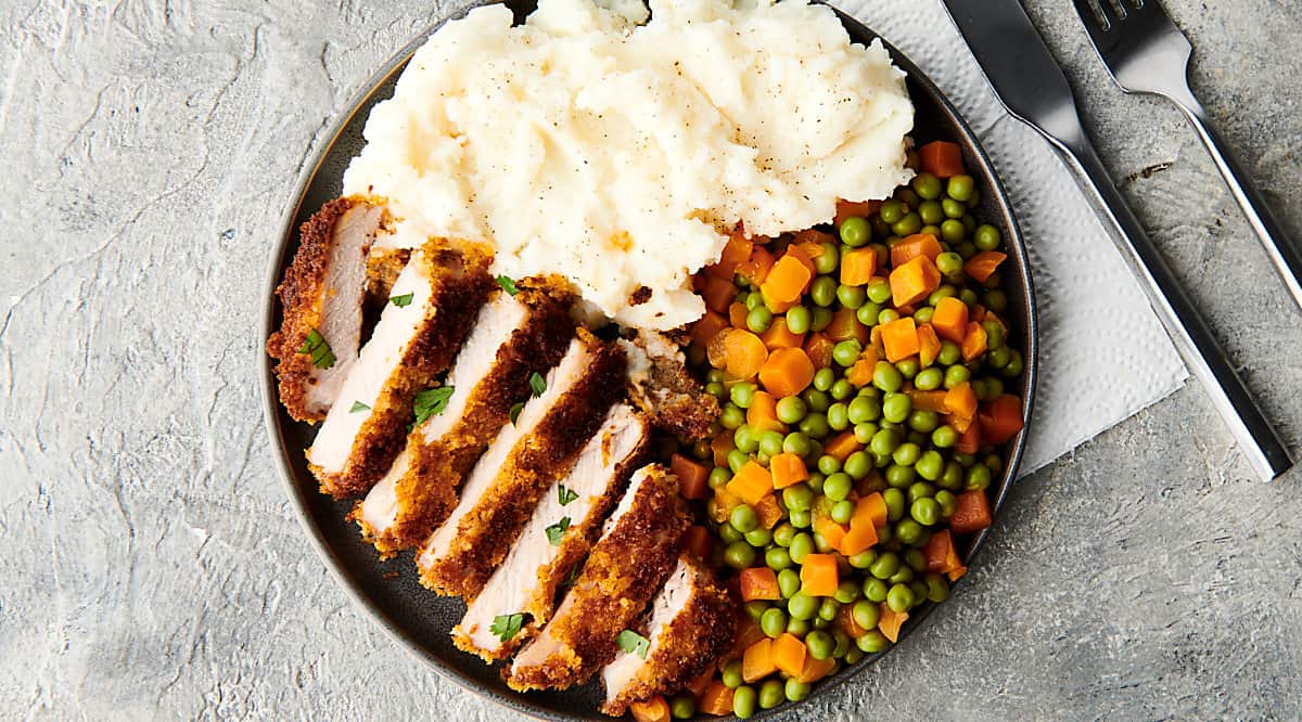 baked pork chop on plate with mashed potatoes and veggies above