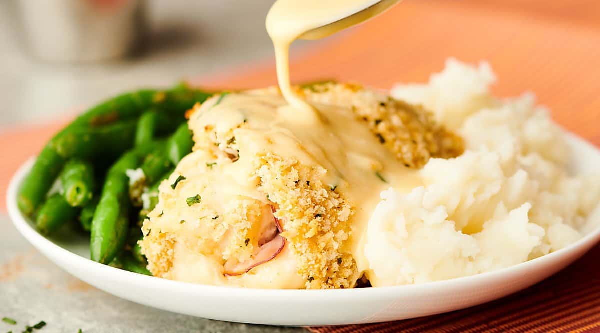chicken cordon bleu on plate with mashed potatoes and green beans