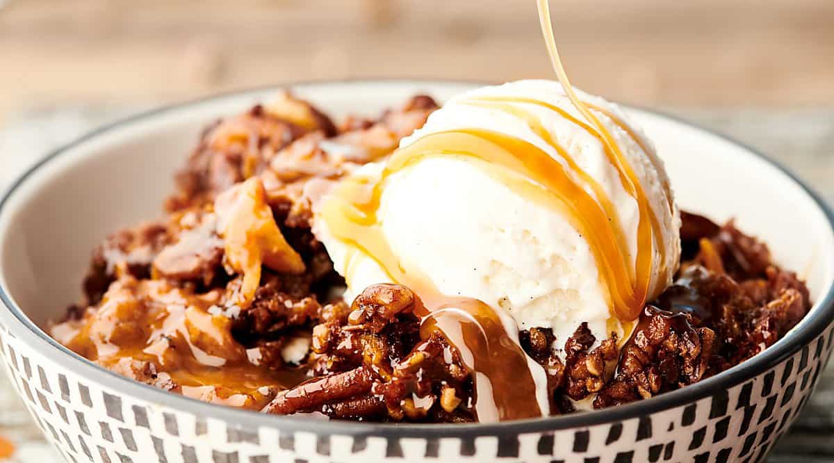 bowl of slow cooker carrot cake with ice cream and caramel