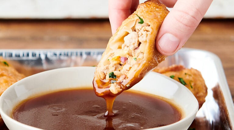 egg roll being dipped in sauce