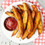 potato wedges on plate with ketchup above