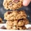 vegan oatmeal cookies stacked on plate, one being lifted off