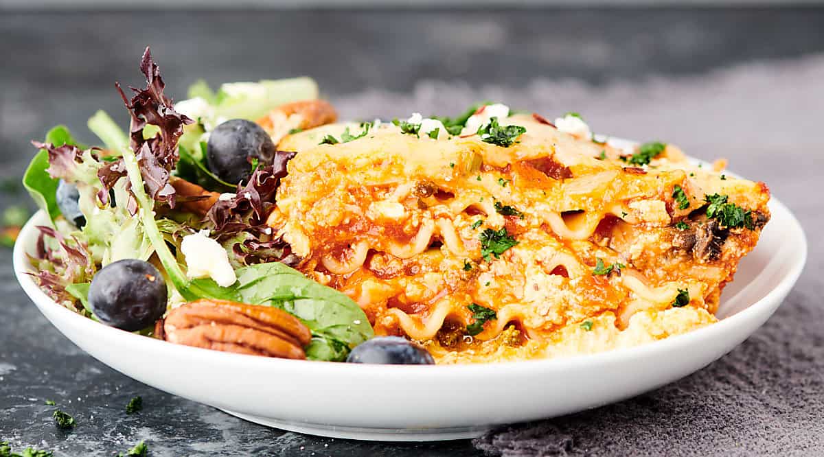 slice of vegetarian lasagna on plate with side salad
