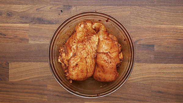 chicken breasts in mixing bowl with spice rub