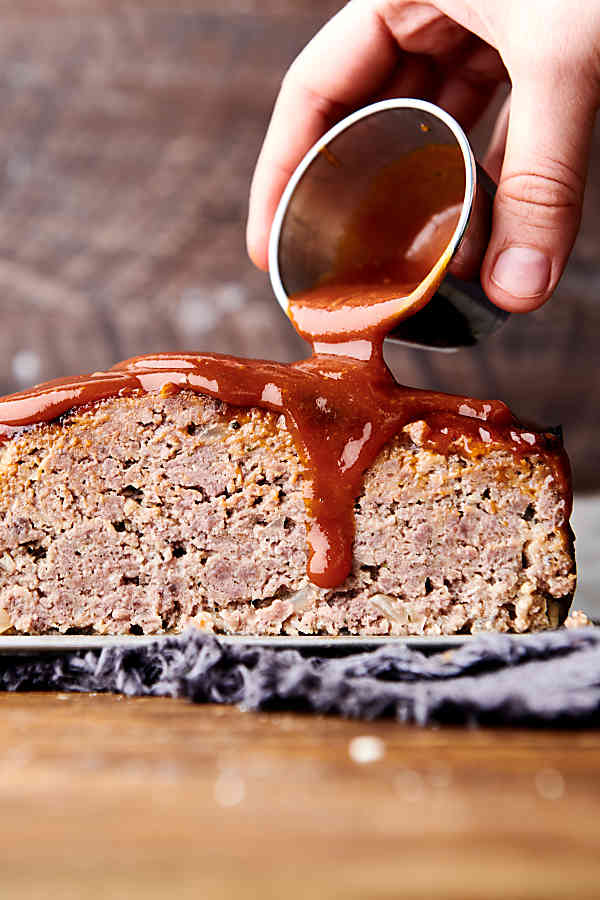 slice of air fryer meatloaf being drizzled with sauce