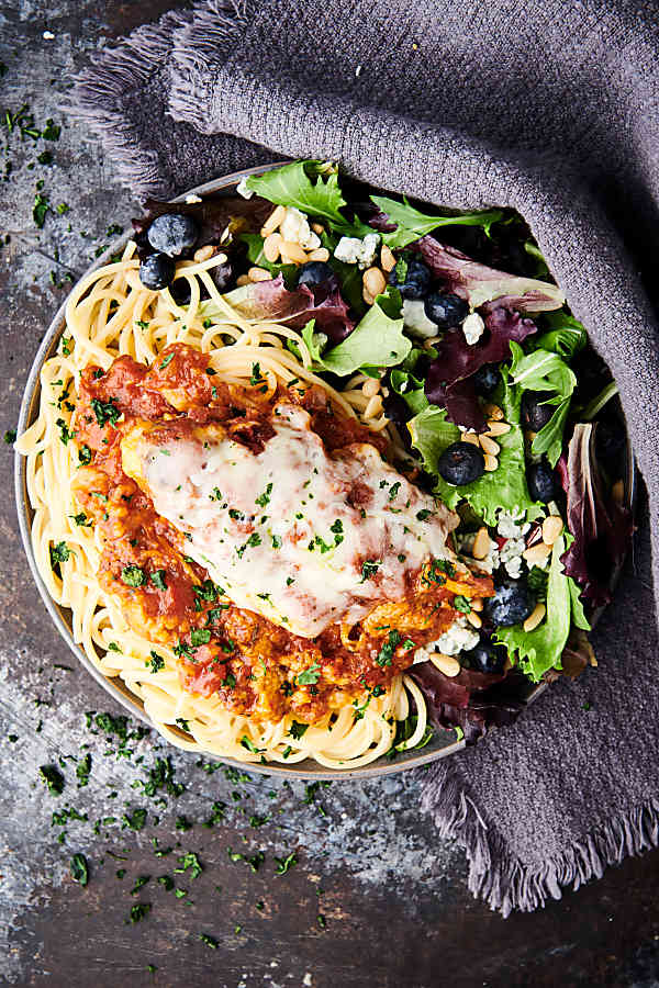 plate of crockpot chicken parmesan with salad above