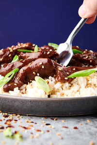 closeup of slow cooker mongolian beef on plate over rice