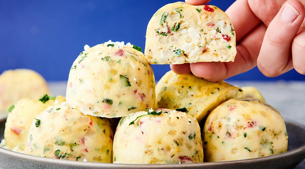 instant pot egg bites stacked on plate, one being lifted
