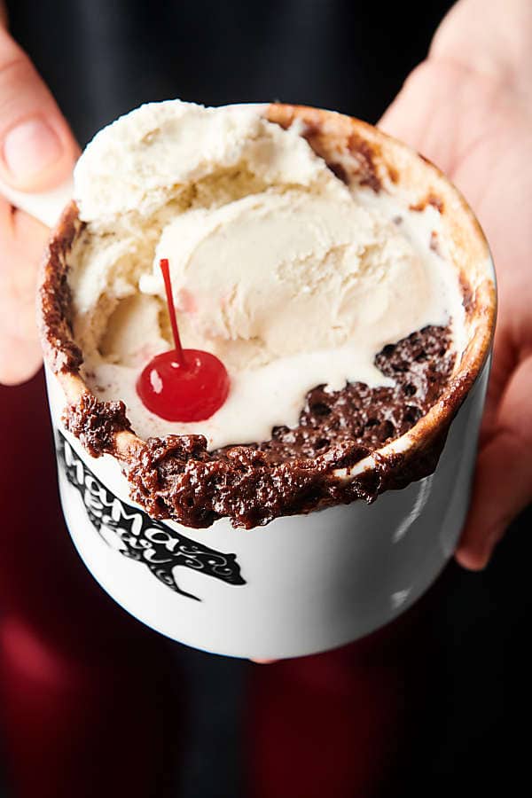 chocolate mug cake with ice cream and cherry held