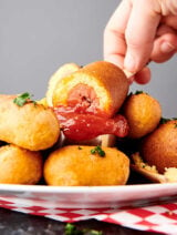 air fryer corn dogs on plate, one being dipped into ketchup