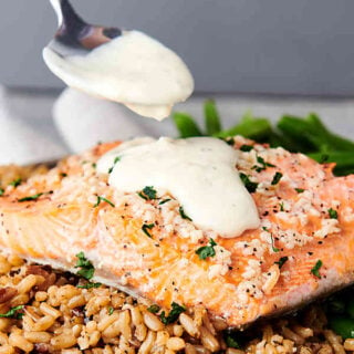 baked salmon over rice being drizzled with honey lemon sauce