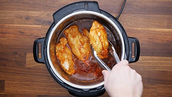 cooked chicken being taken out of instant pot