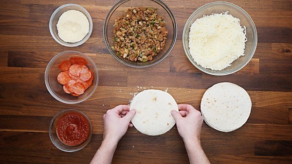 tortilla being placed on top of filled quesadilla