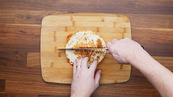 pizza quesadilla being sliced on cutting board