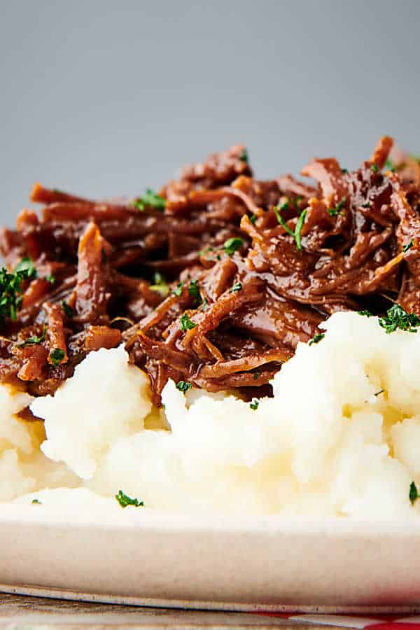 closeup of slow cooker flank steak on mashed potatoes