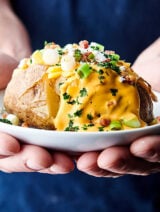 plate with instant pot baked potato held two hands