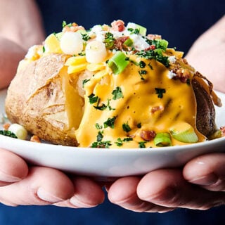 plate with instant pot baked potato held two hands